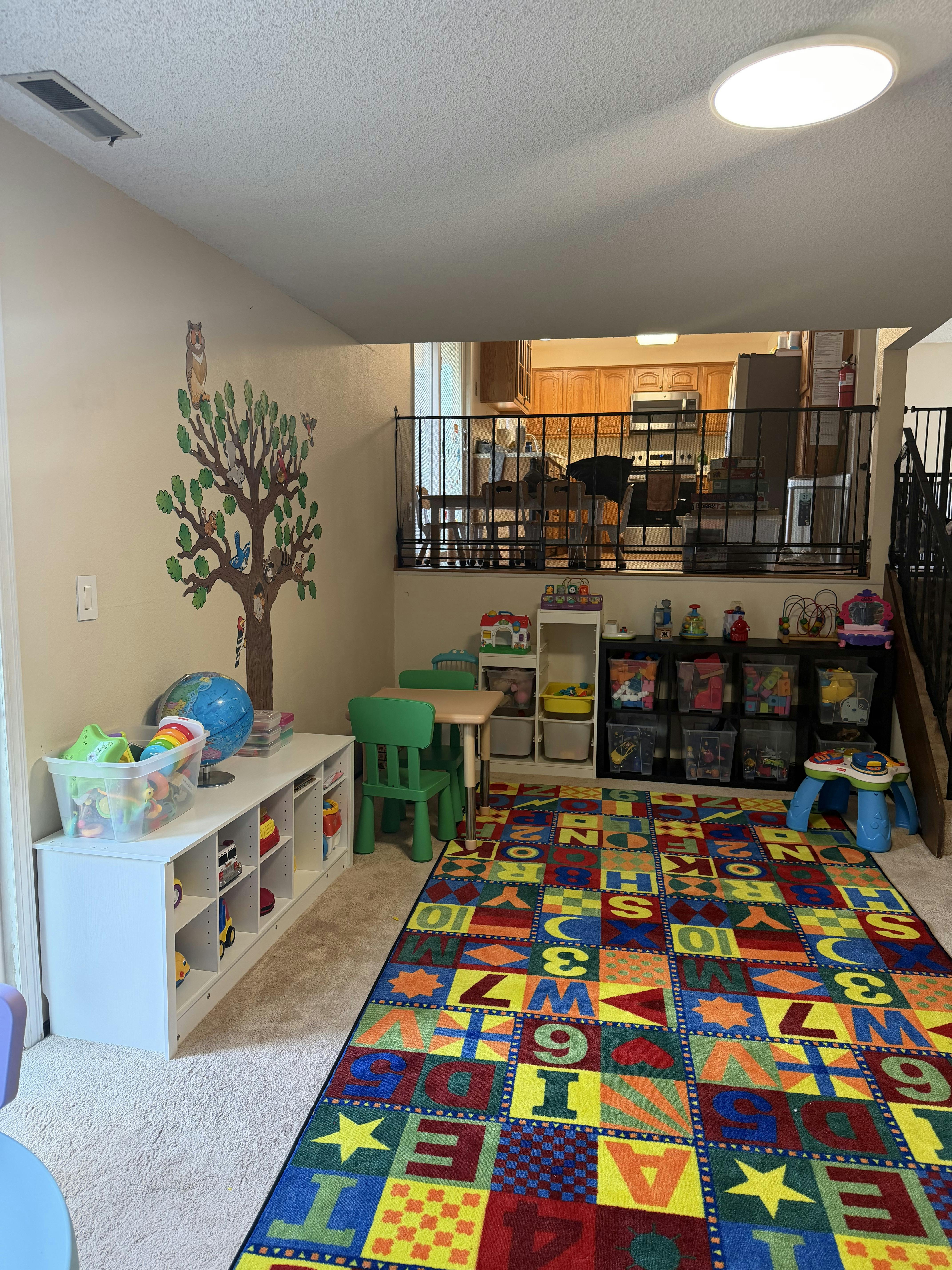Playroom with colorful alphabet rug, small table, chairs, and toy storage