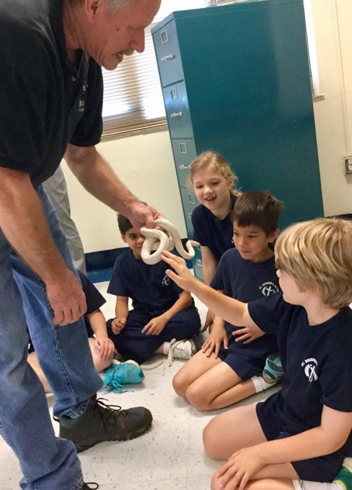 Person holding a white snake for children to see
