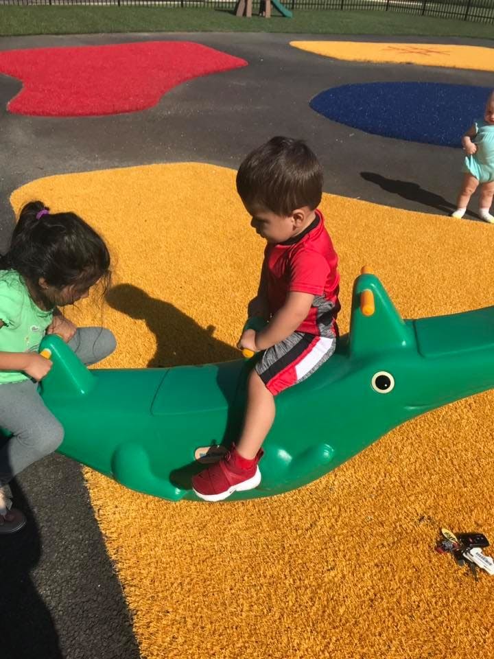 Two children on a green alligator-shaped seesaw