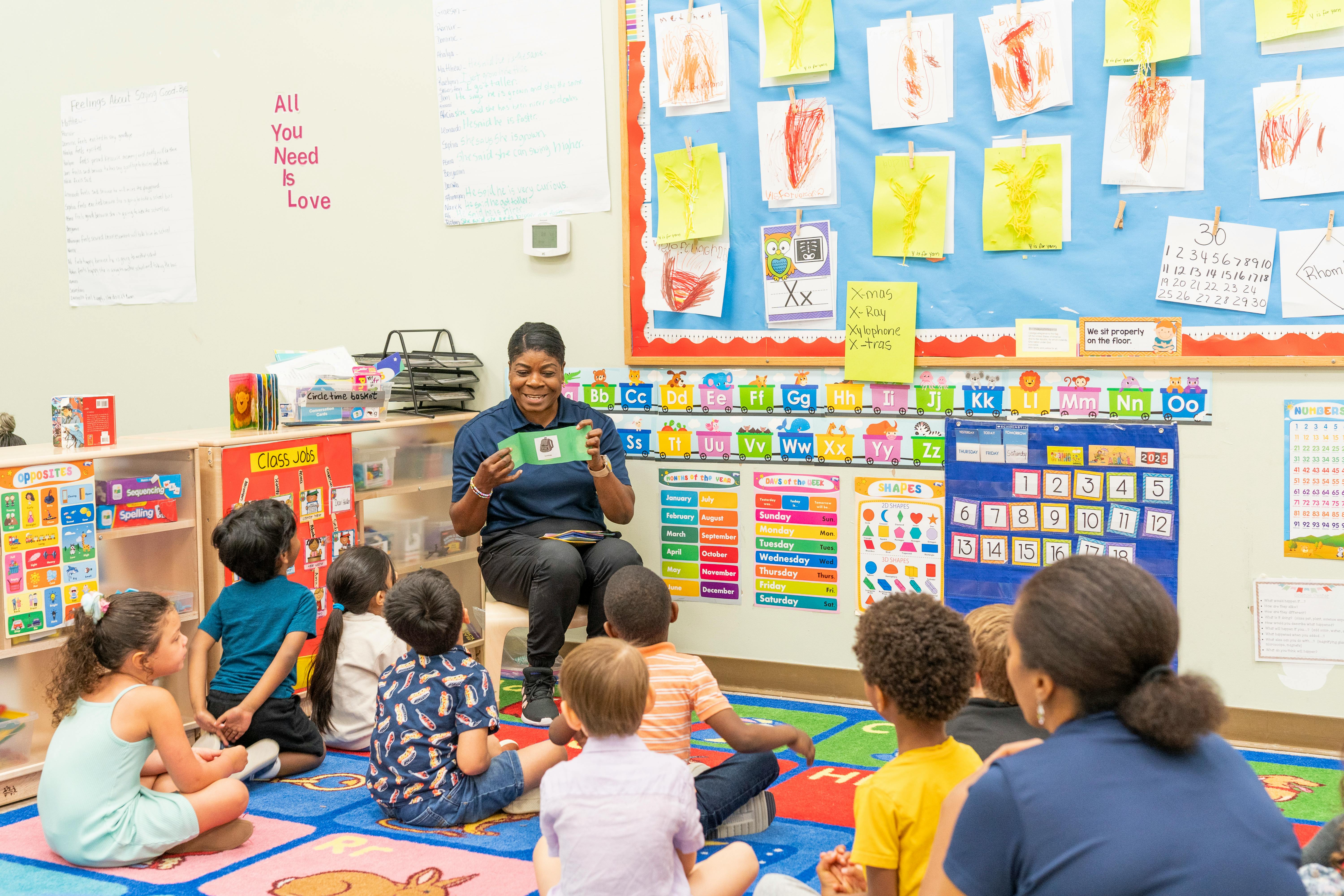 Person showing a green paper to children in a classroom