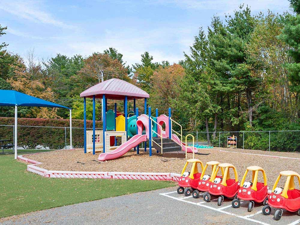 Colorful playground with slides, play structure, and parked toy cars