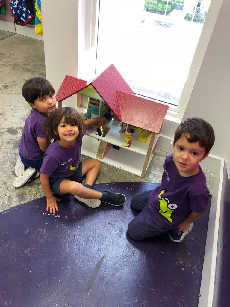 Three children playing with a dollhouse