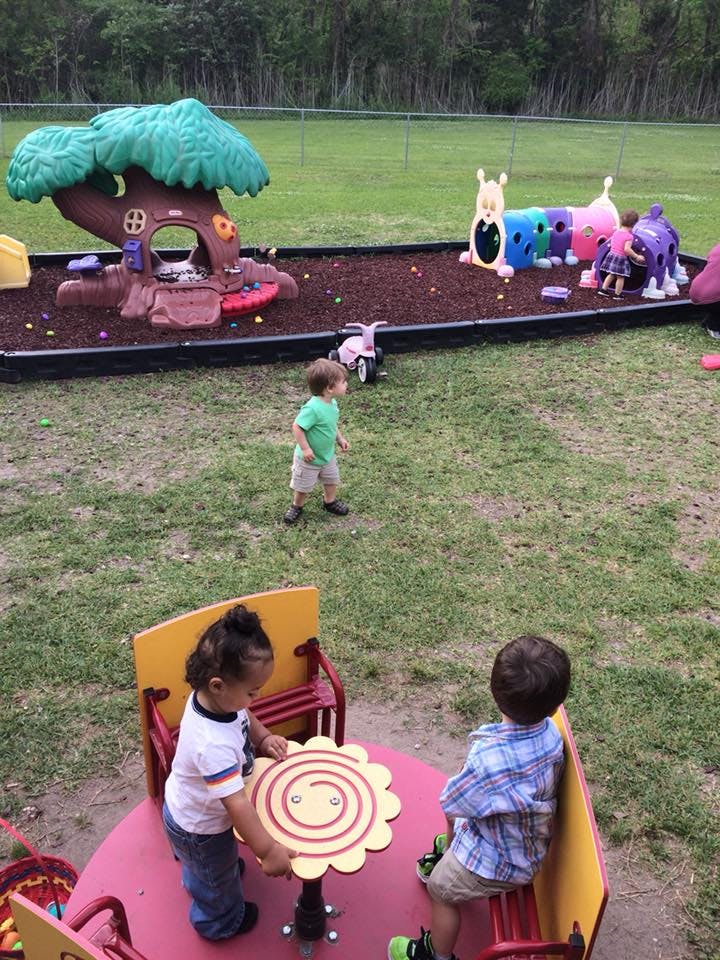 Children playing on a playground with a treehouse and other play equipment