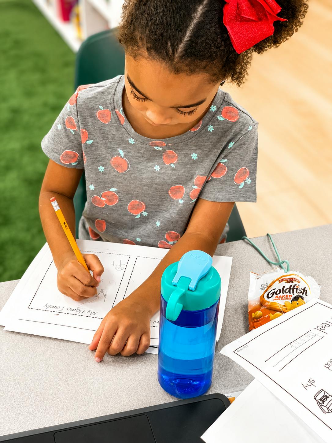 Child writing on a worksheet labeled My Home Family at a desk