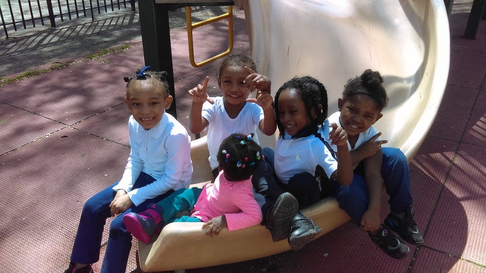 Five children sitting on a playground slide