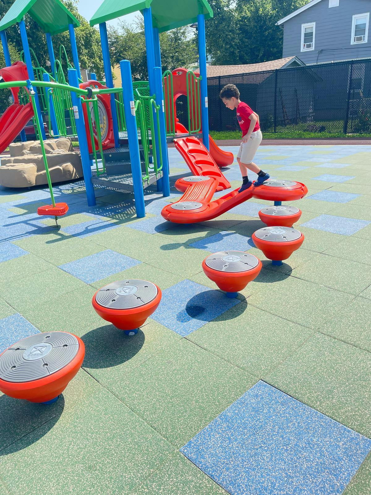 Child balancing on stepping stone playground equipment