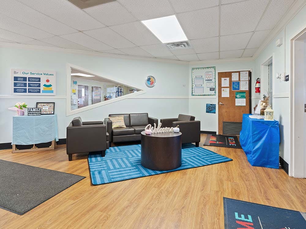 Lobby area with black sofas, a blue rug, and a triangular window