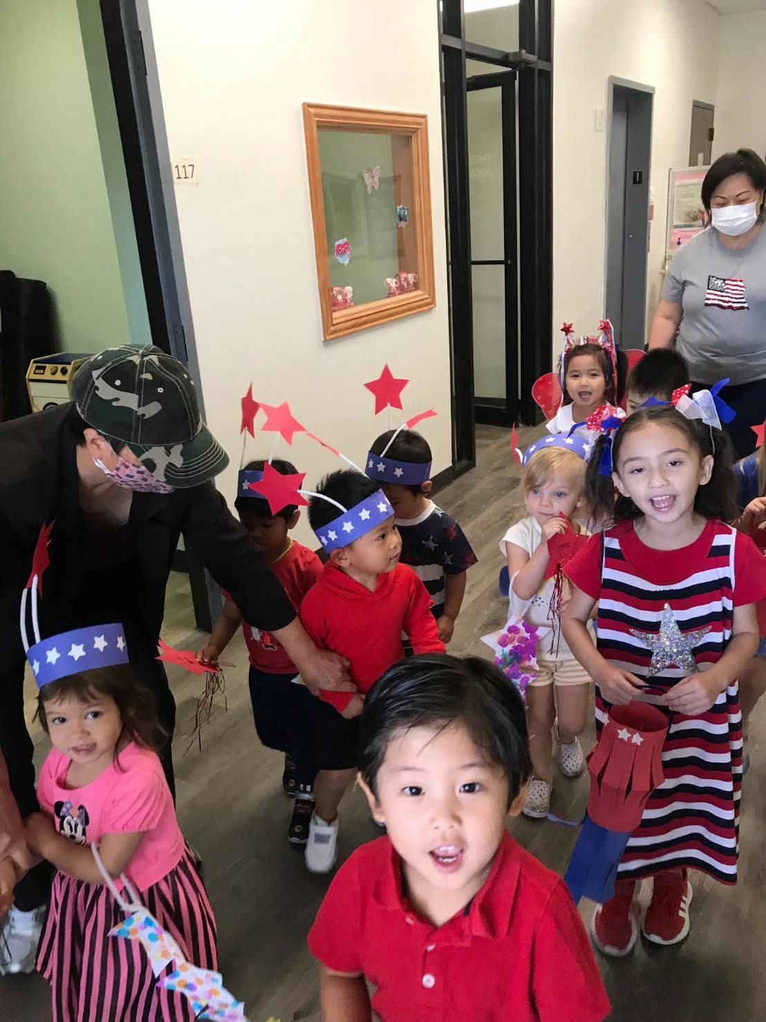 Adults and children in a hallway, some wearing patriotic headbands
