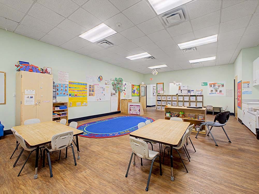 Empty classroom with small tables, chairs, and colorful decorations on the walls