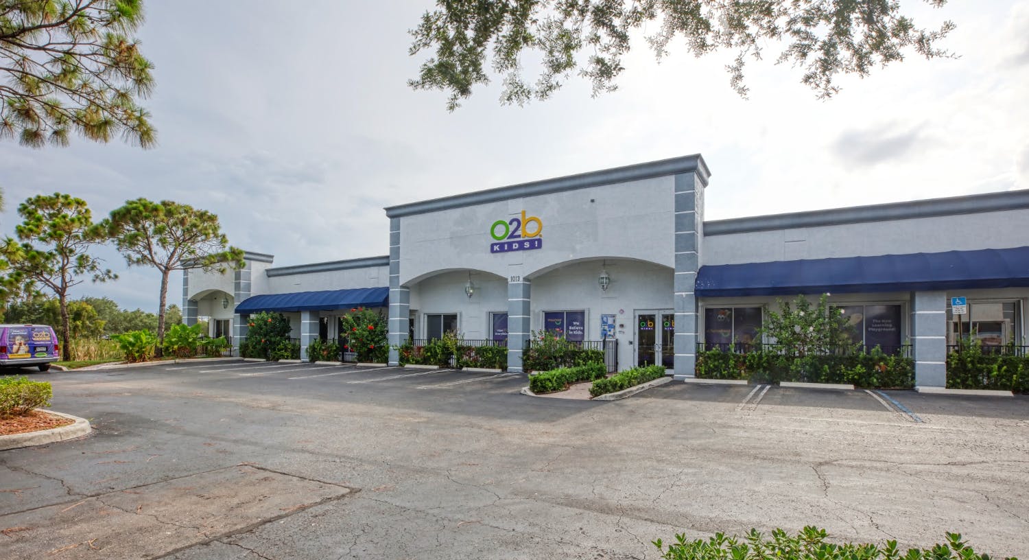 Exterior of O2B Kids! building with parking lot and trees