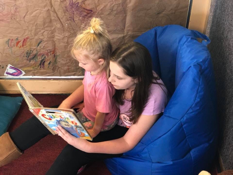 Two children sitting together reading a book
