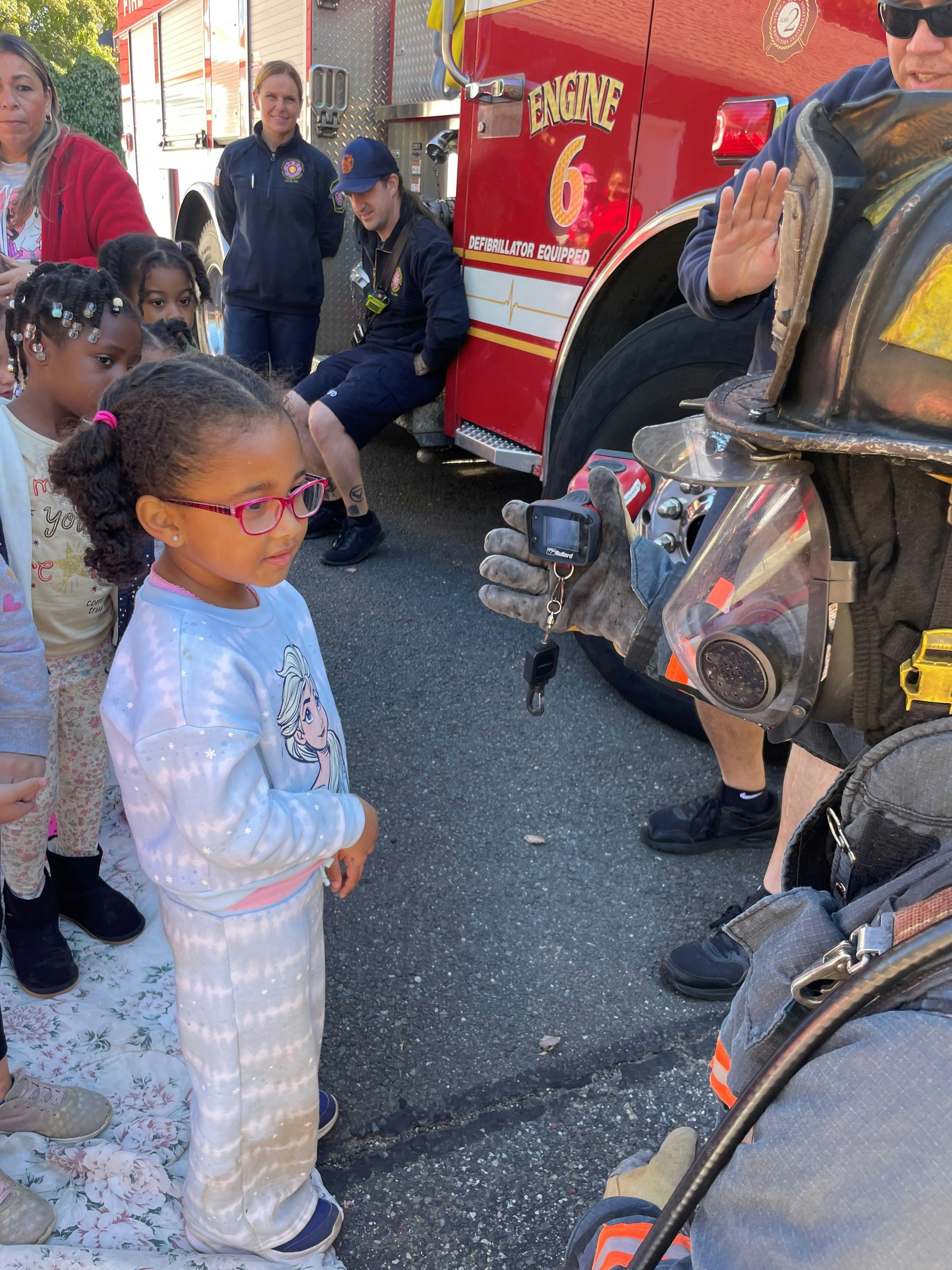 Child looking at a thermal imaging camera held by a firefighter