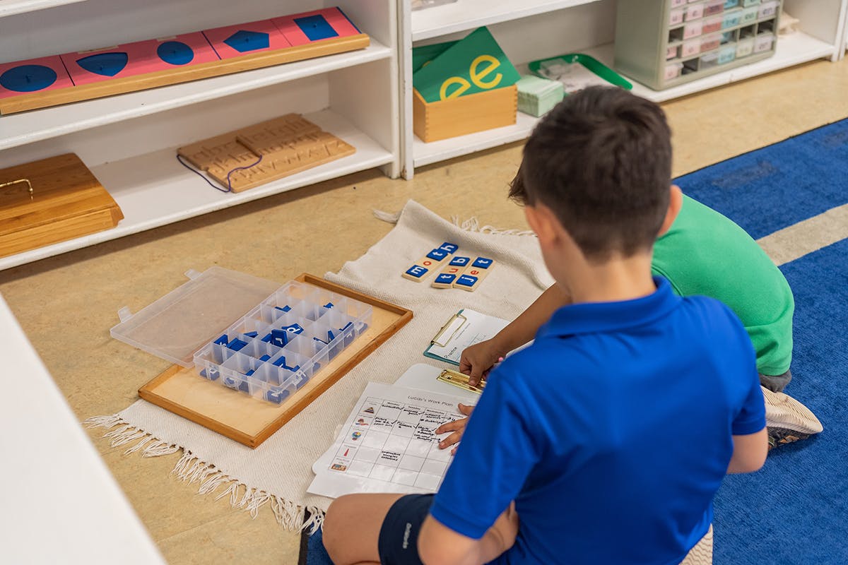 Two children working on an activity on the floor in a classroom