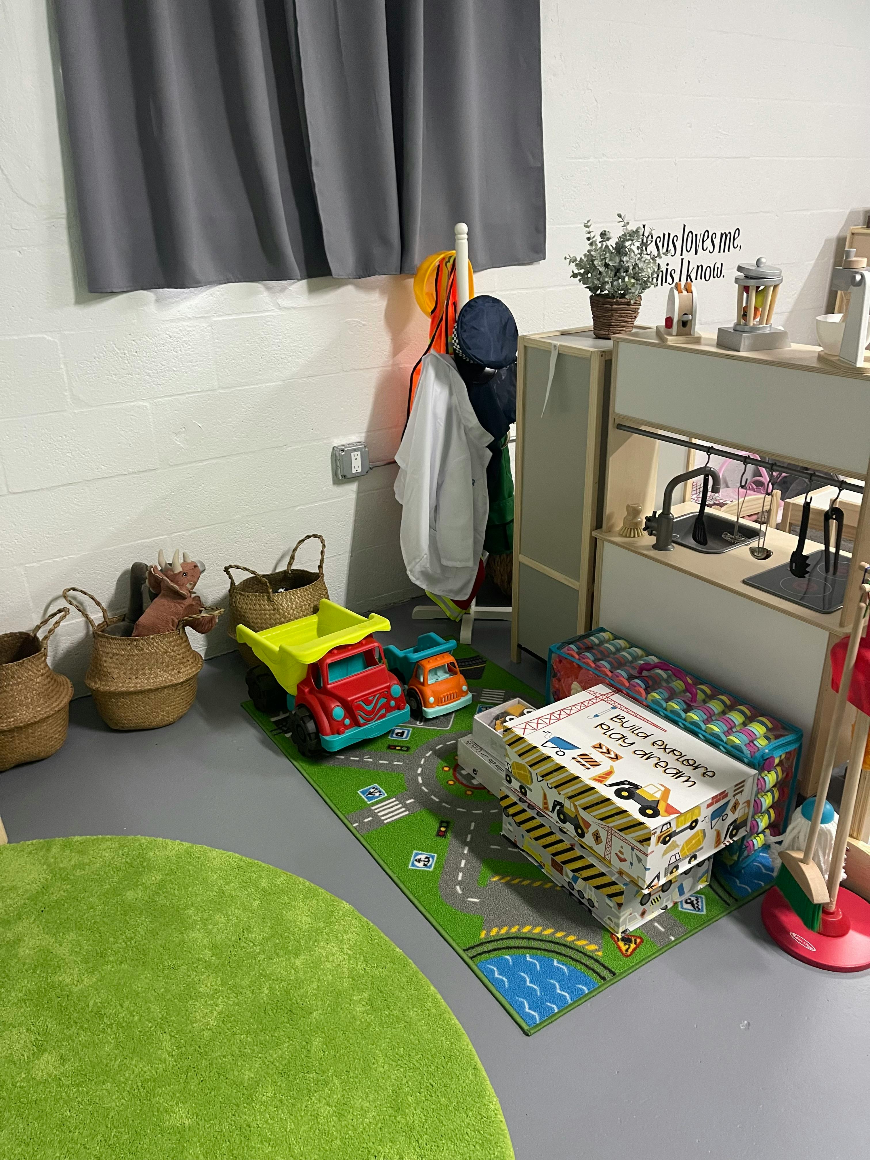 Children's play area with toy trucks on a road rug and a play kitchen
