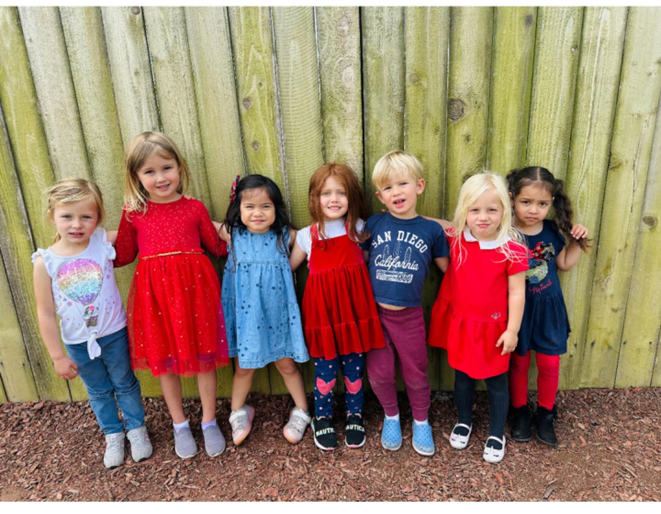 Group of children standing in front of a wooden fence