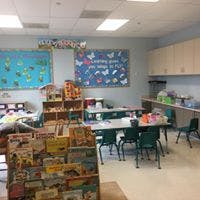 classroom with tables, chairs, and shelves of books and toys