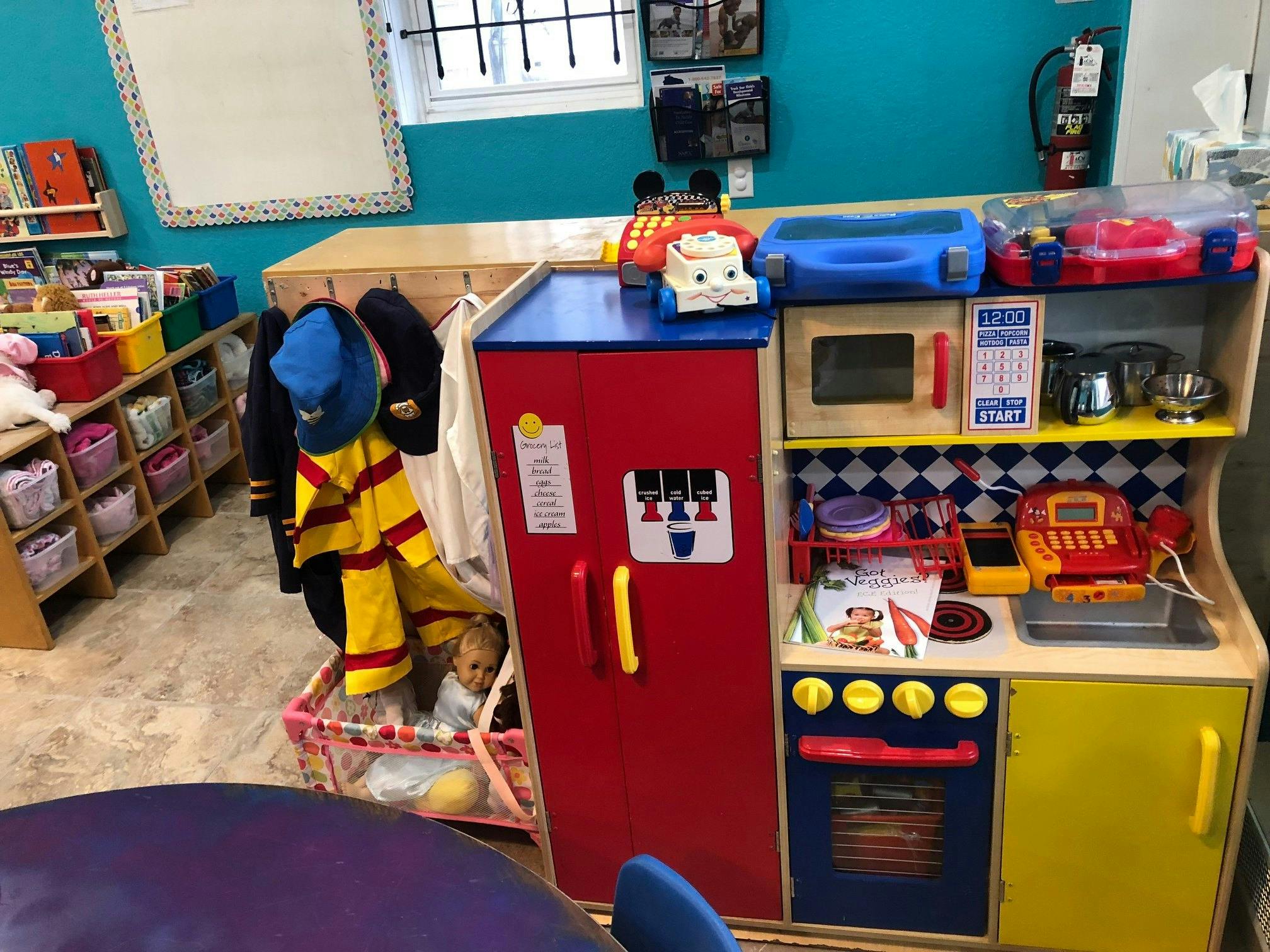 Play kitchen set with refrigerator, stove, and microwave in a classroom