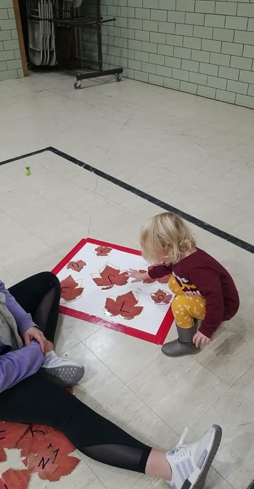 Child playing with leaf cutouts on the floor