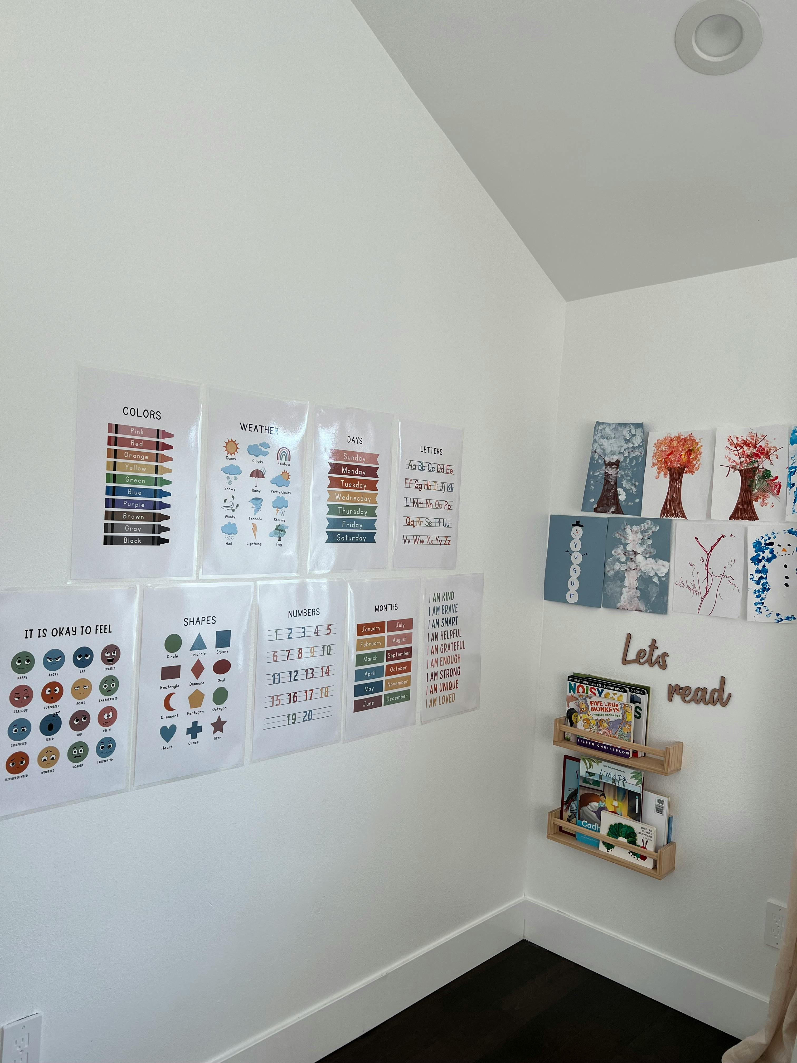 Educational posters on a white wall with a small bookshelf holding books