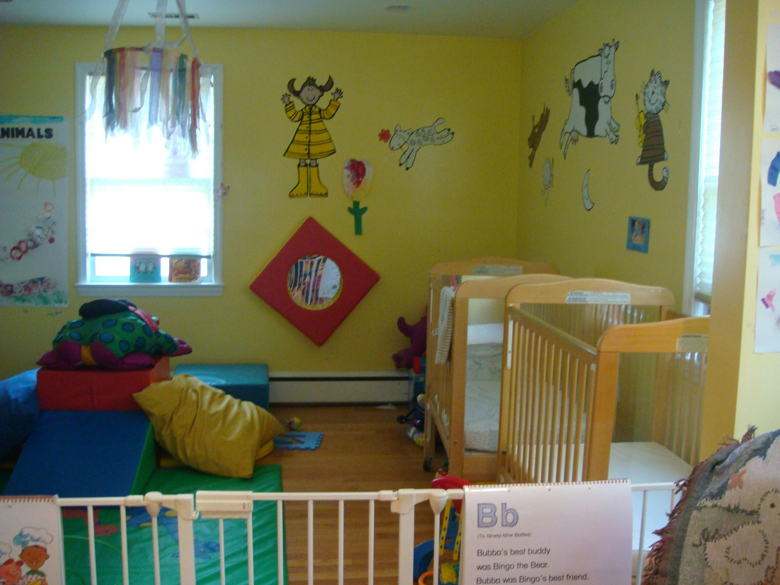 Two cribs in a room with yellow walls and colorful wall decorations