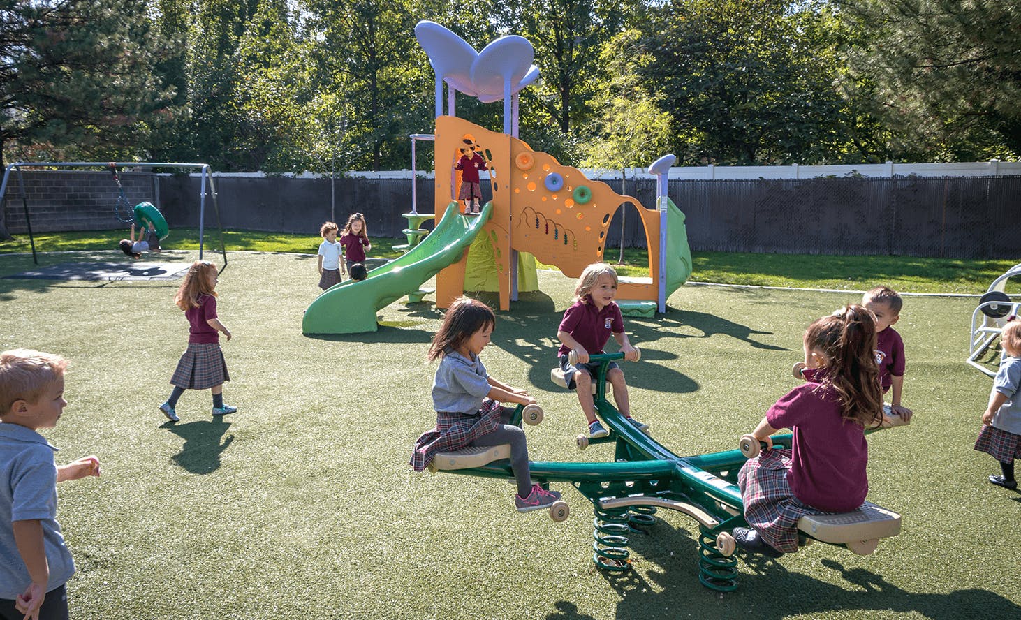 Children playing on a playground with a slide and seesaw