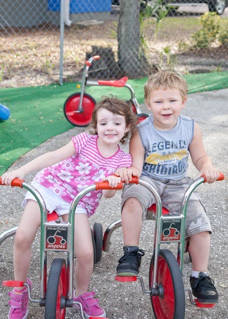 Two children sitting on tricycles