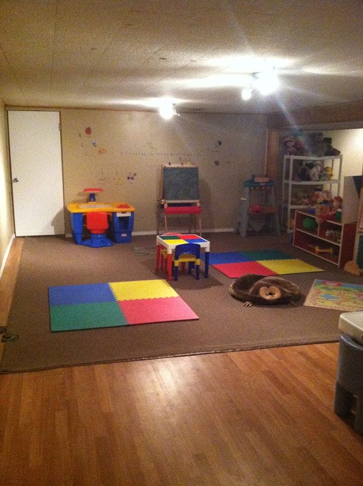 Playroom with small table and chairs, easel, and colorful floor mats