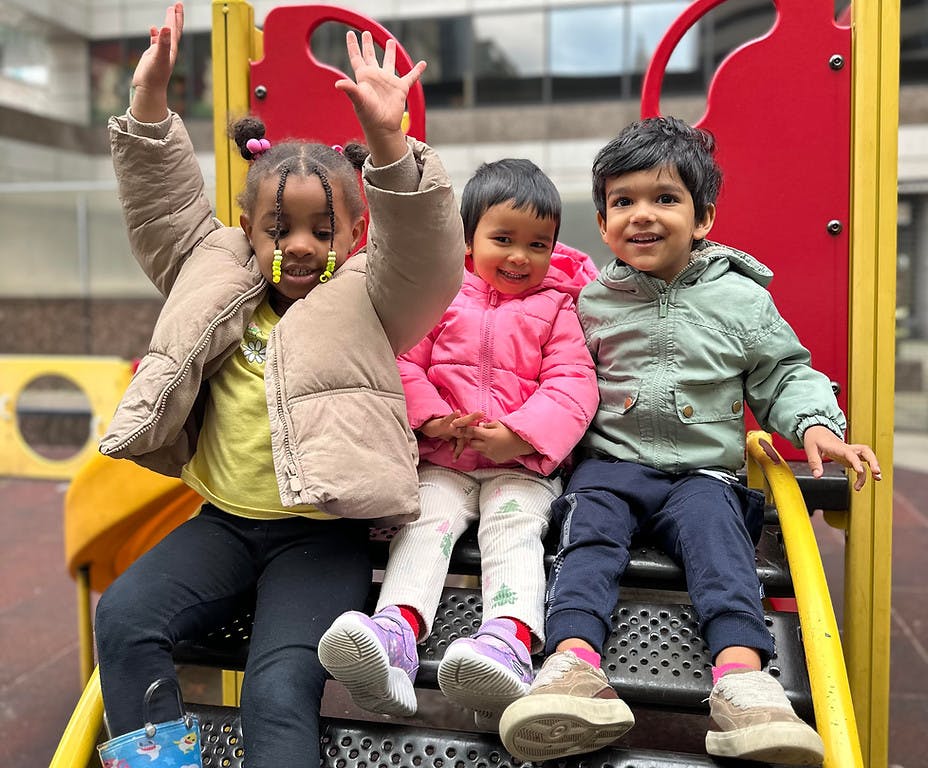 Three children sitting on playground steps