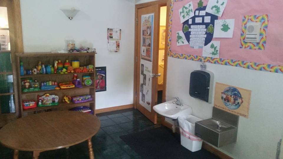 Classroom with a wooden shelf of toys, a round table, and a sink