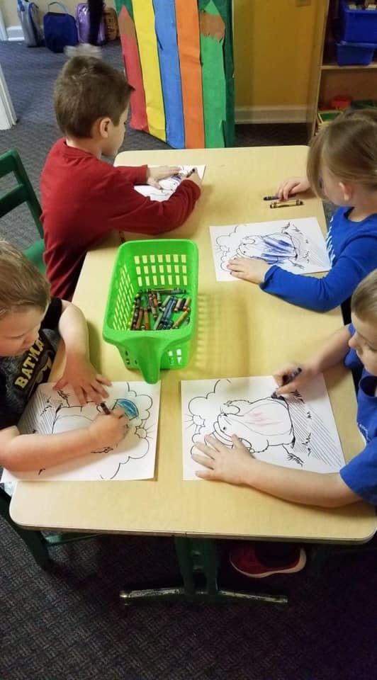 Children coloring at a table in a classroom