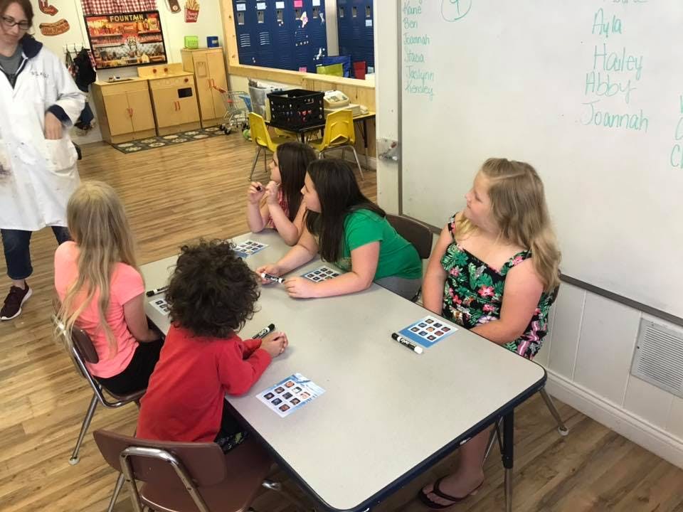 People and children sitting at a table in a classroom