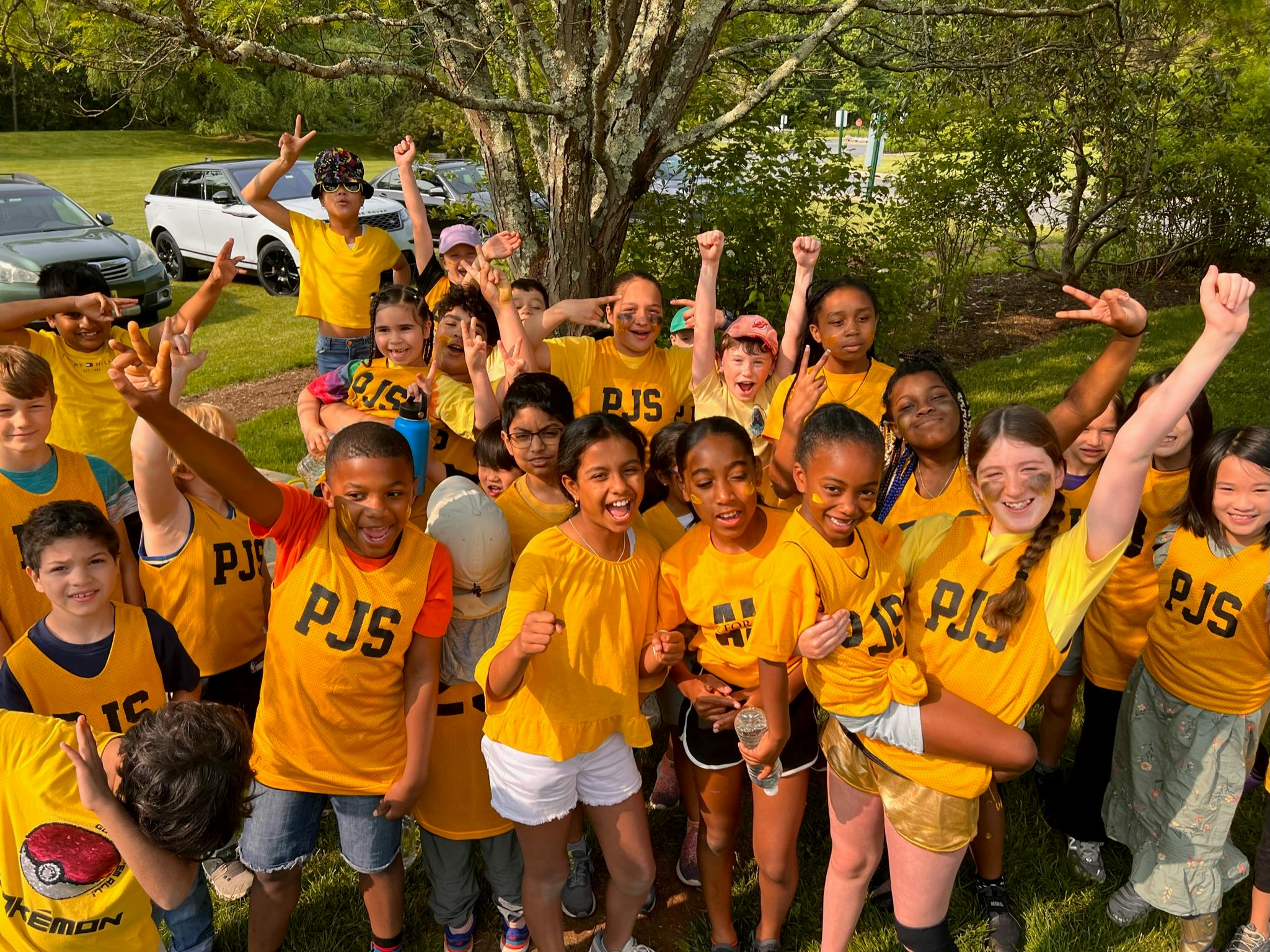 Group of people and children in yellow shirts raising their arms