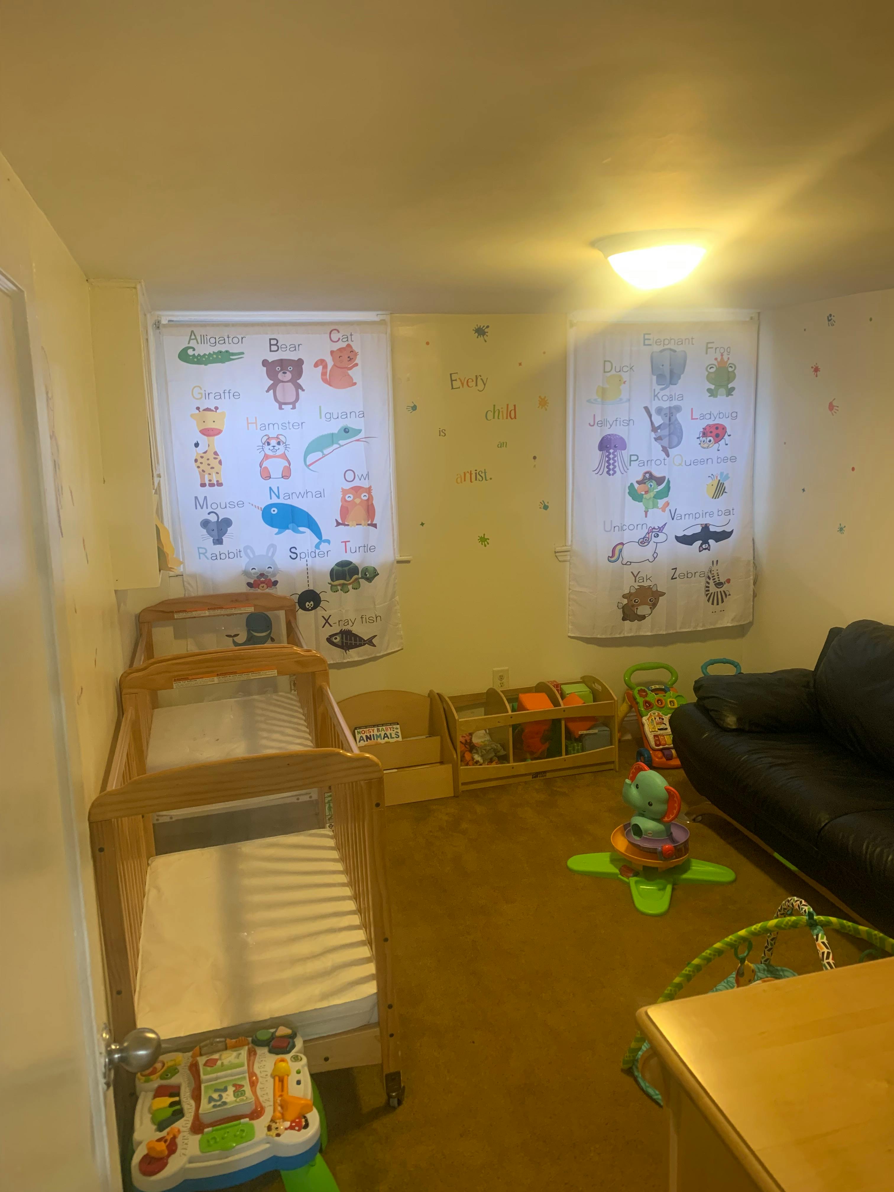 Two cribs in a room with alphabet charts on the wall