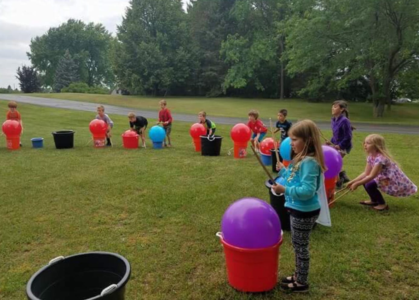 Children playing a game with buckets and balloons outdoors