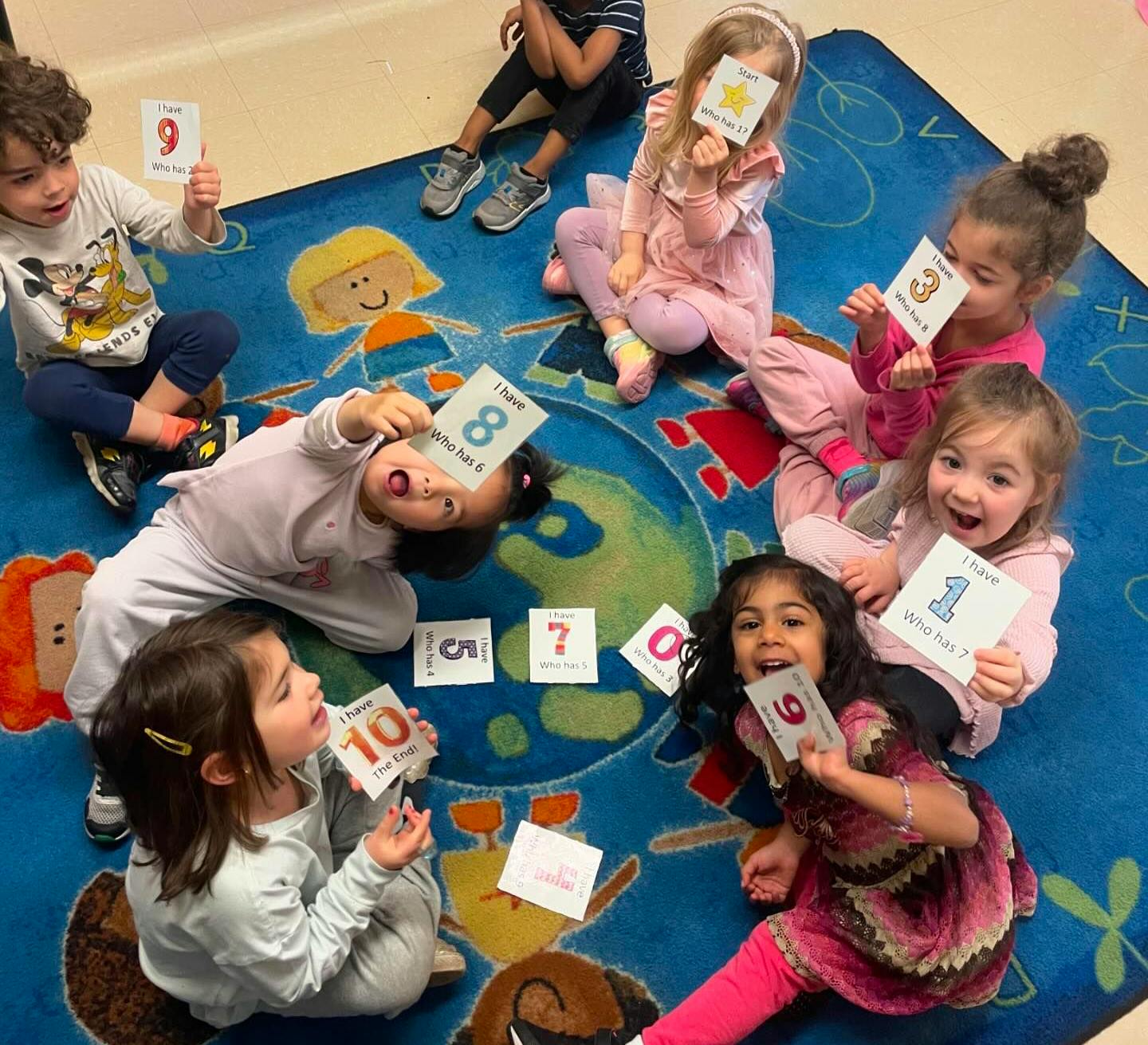 Children sitting on a rug holding up number cards