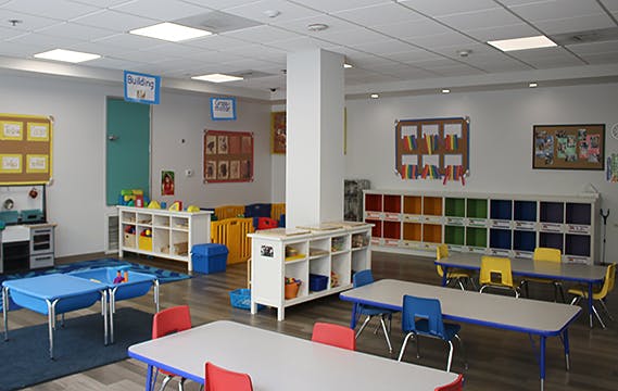 Empty classroom with tables, chairs, and storage shelves