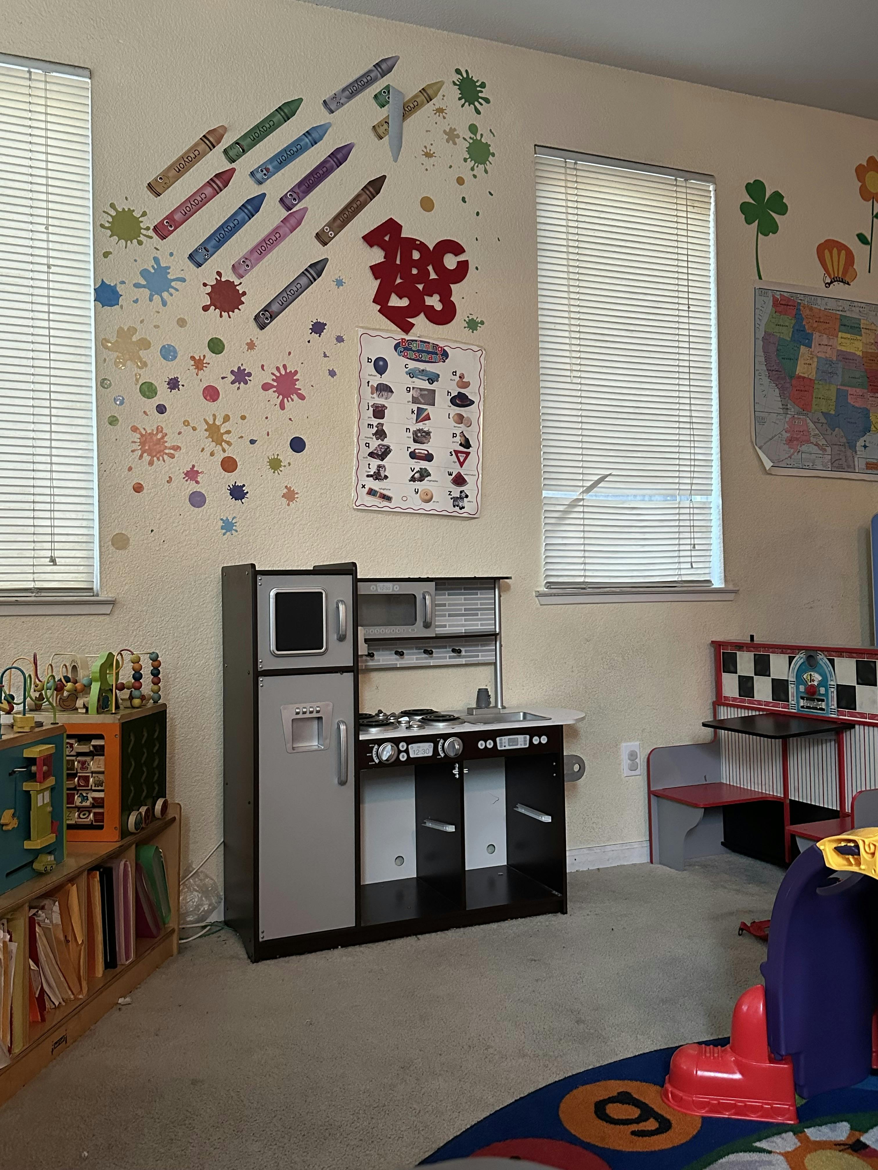 Playroom with a toy kitchen, bookshelves, and wall decals