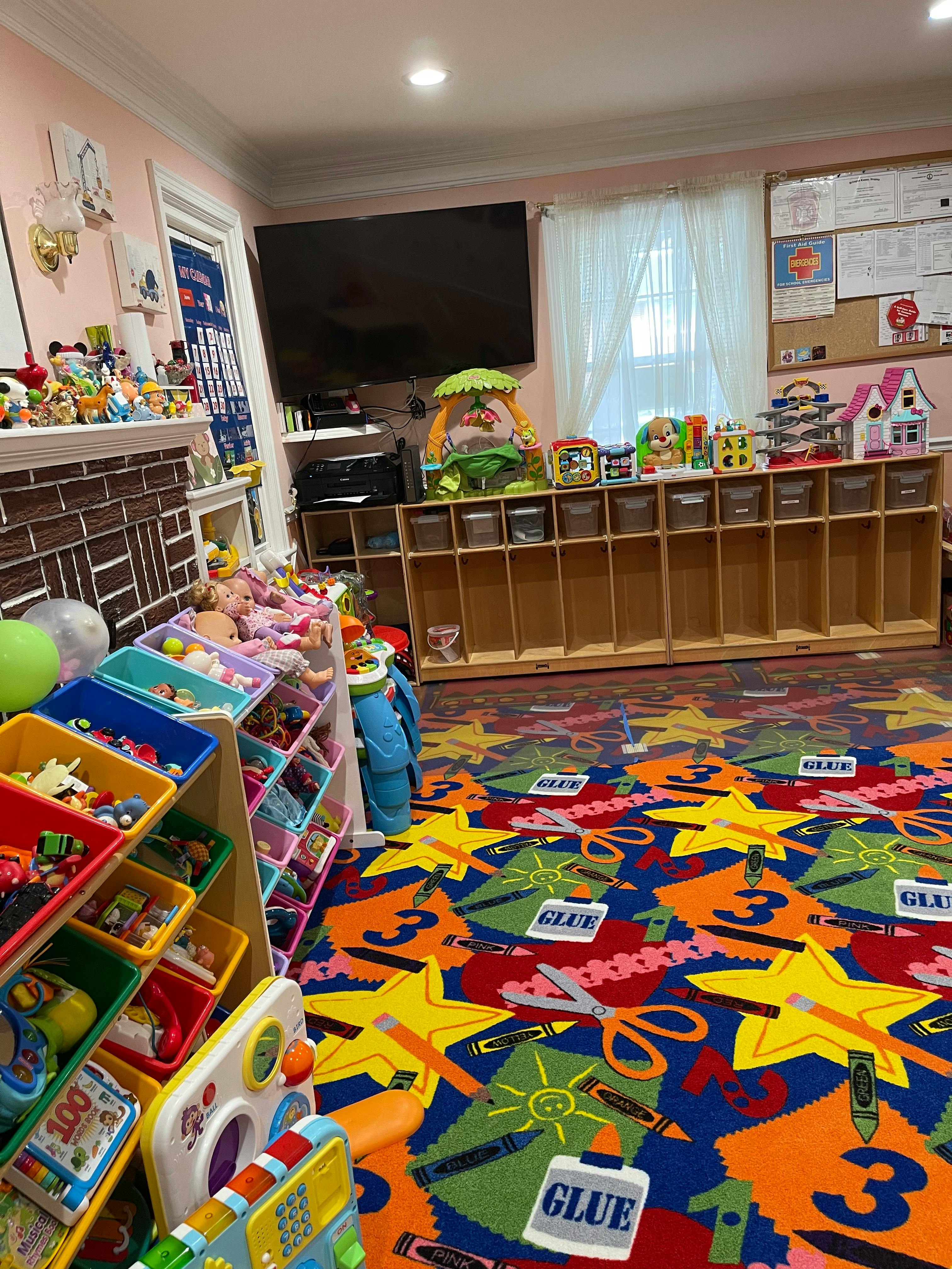 Playroom with colorful rug, toy shelves, and television