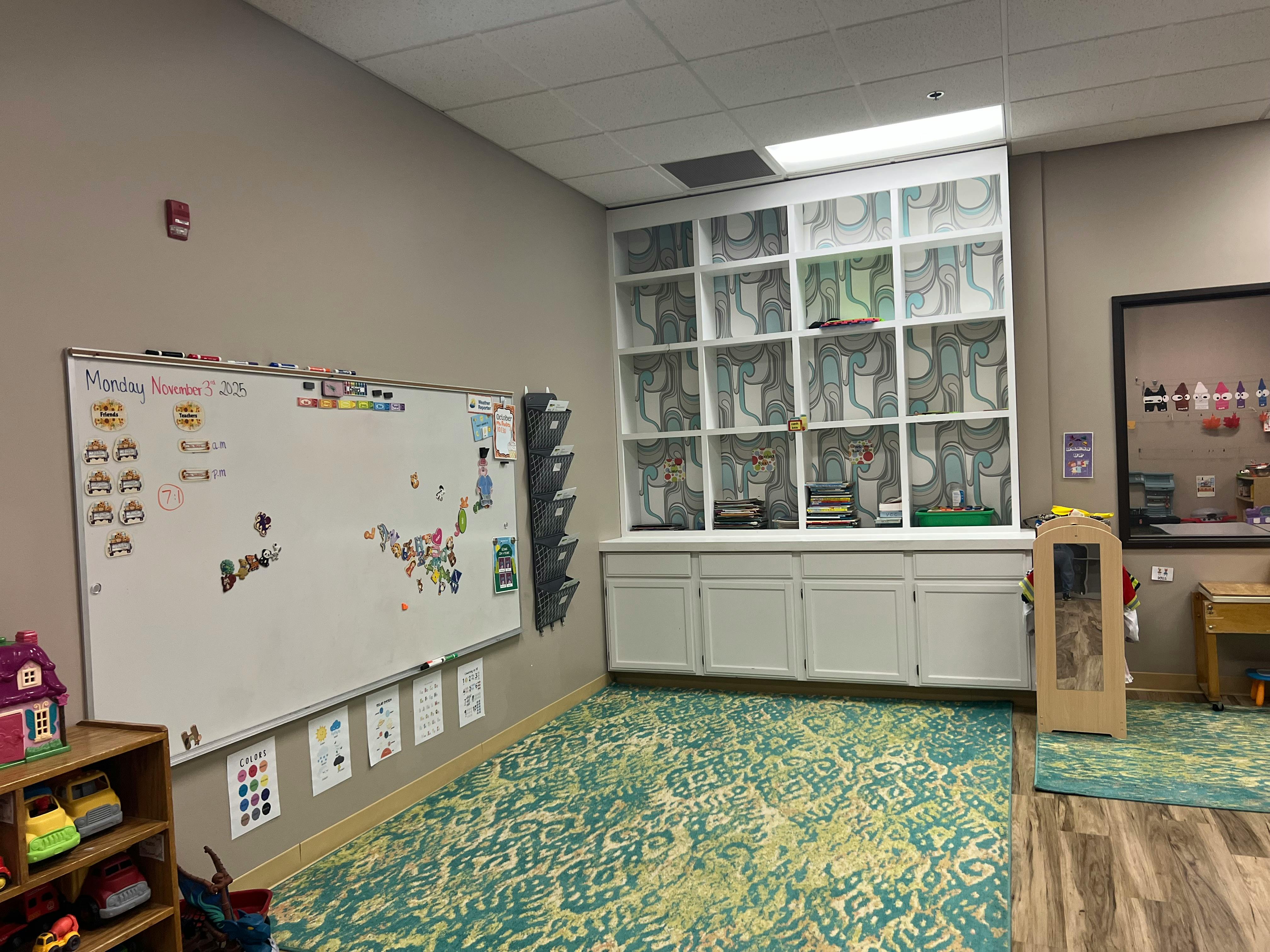 Classroom with a whiteboard, patterned carpet, and storage shelves