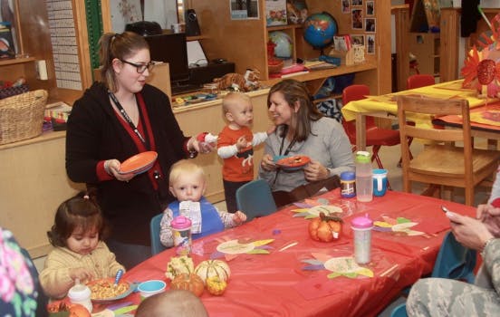 Adults and children at a table in a classroom