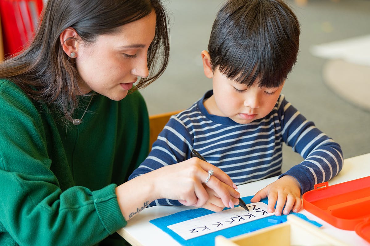 Person helping a child write on paper