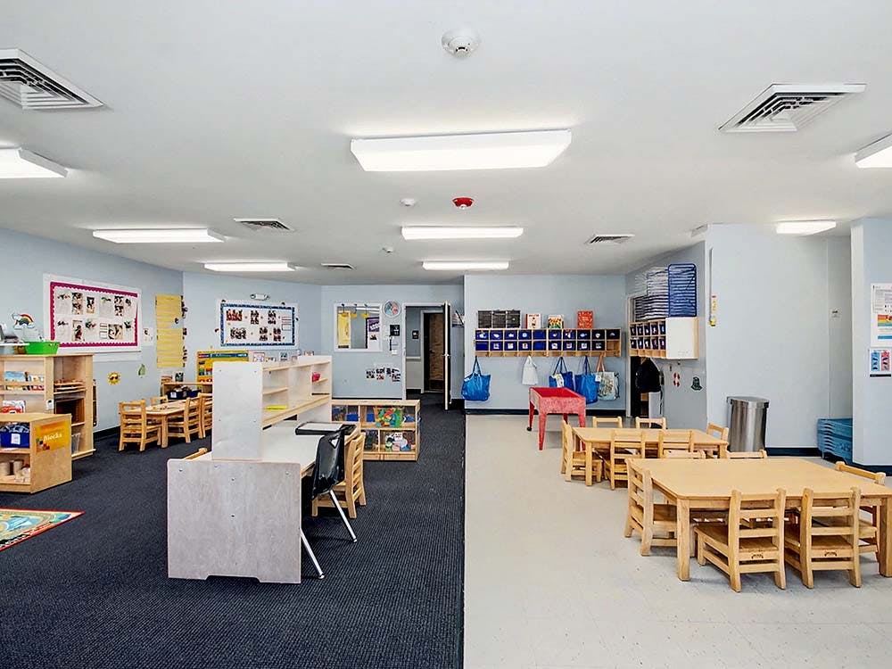 Empty preschool classroom with small tables and chairs