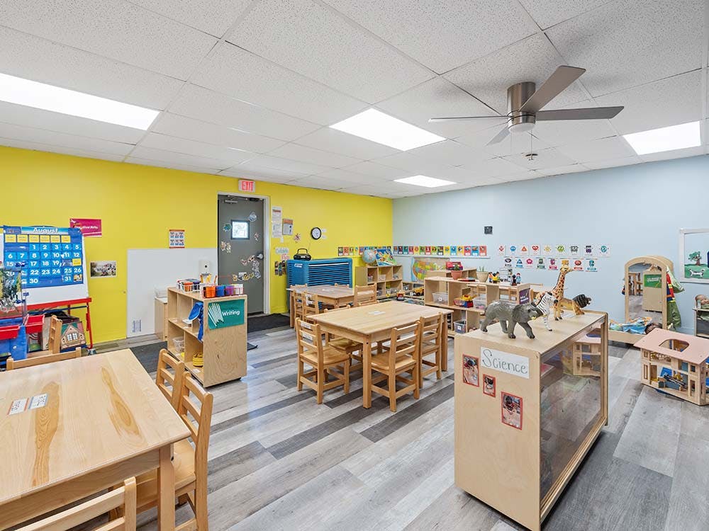 A colorful empty classroom for young children with small tables and chairs