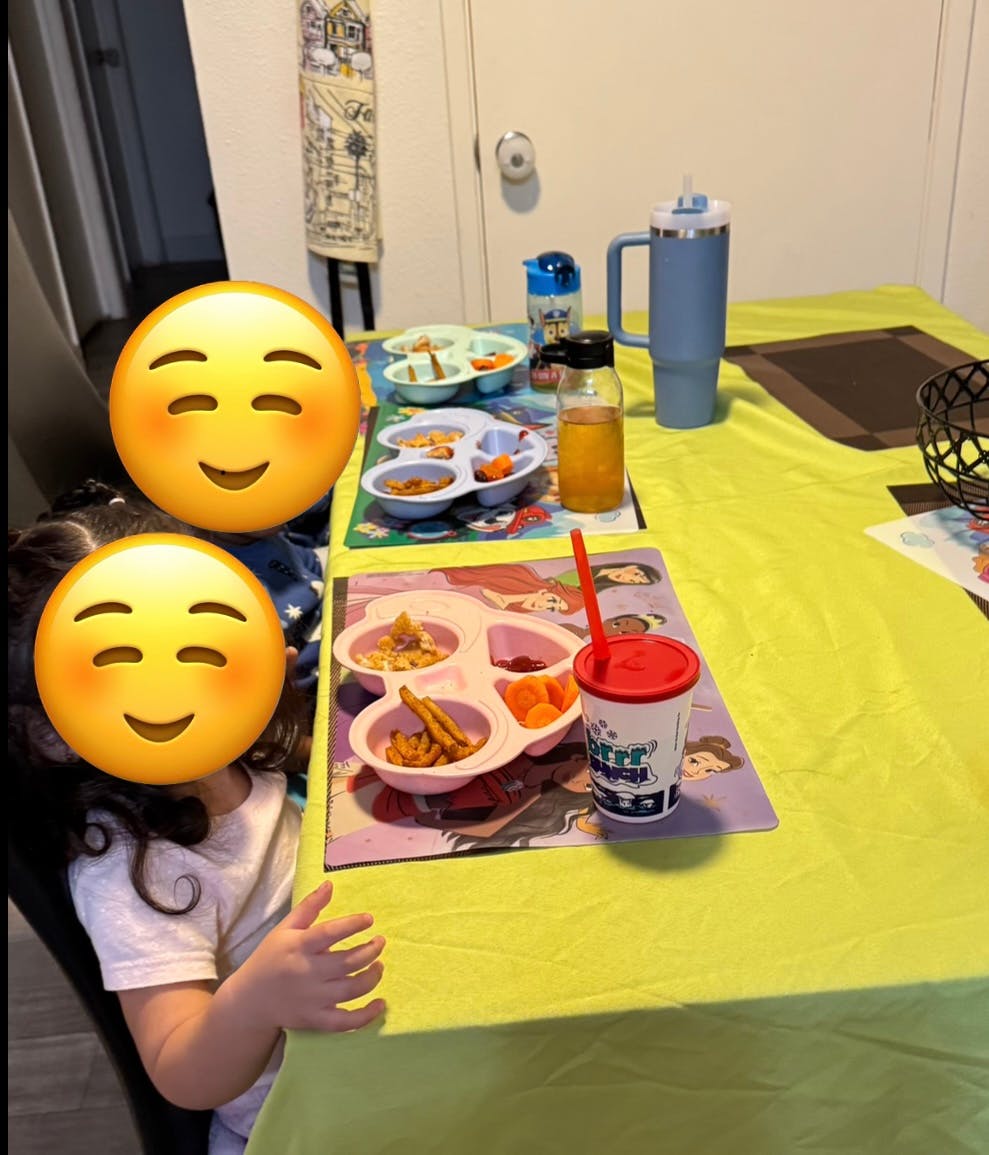 Children sitting at a table with divided plates of food and drinks