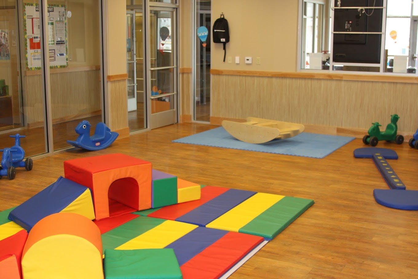 indoor play area with soft colorful play equipment and small ride-on toys