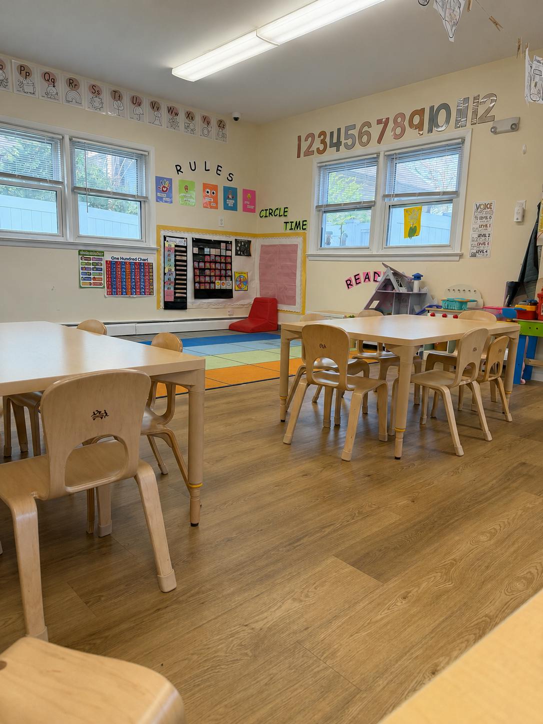 Empty preschool classroom with small tables and chairs and colorful wall decor