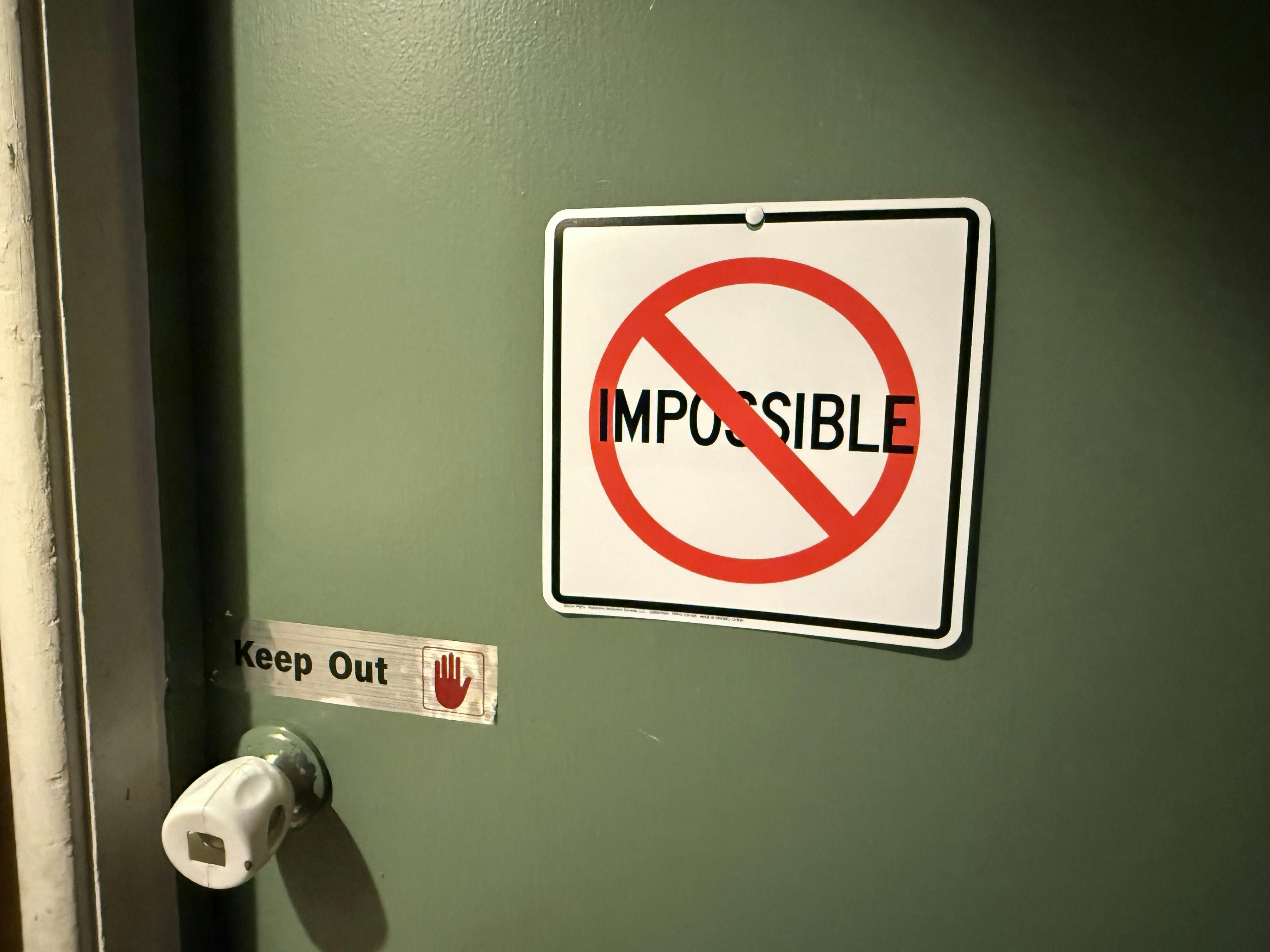 Sign on a door reading Impossible with a prohibition symbol
