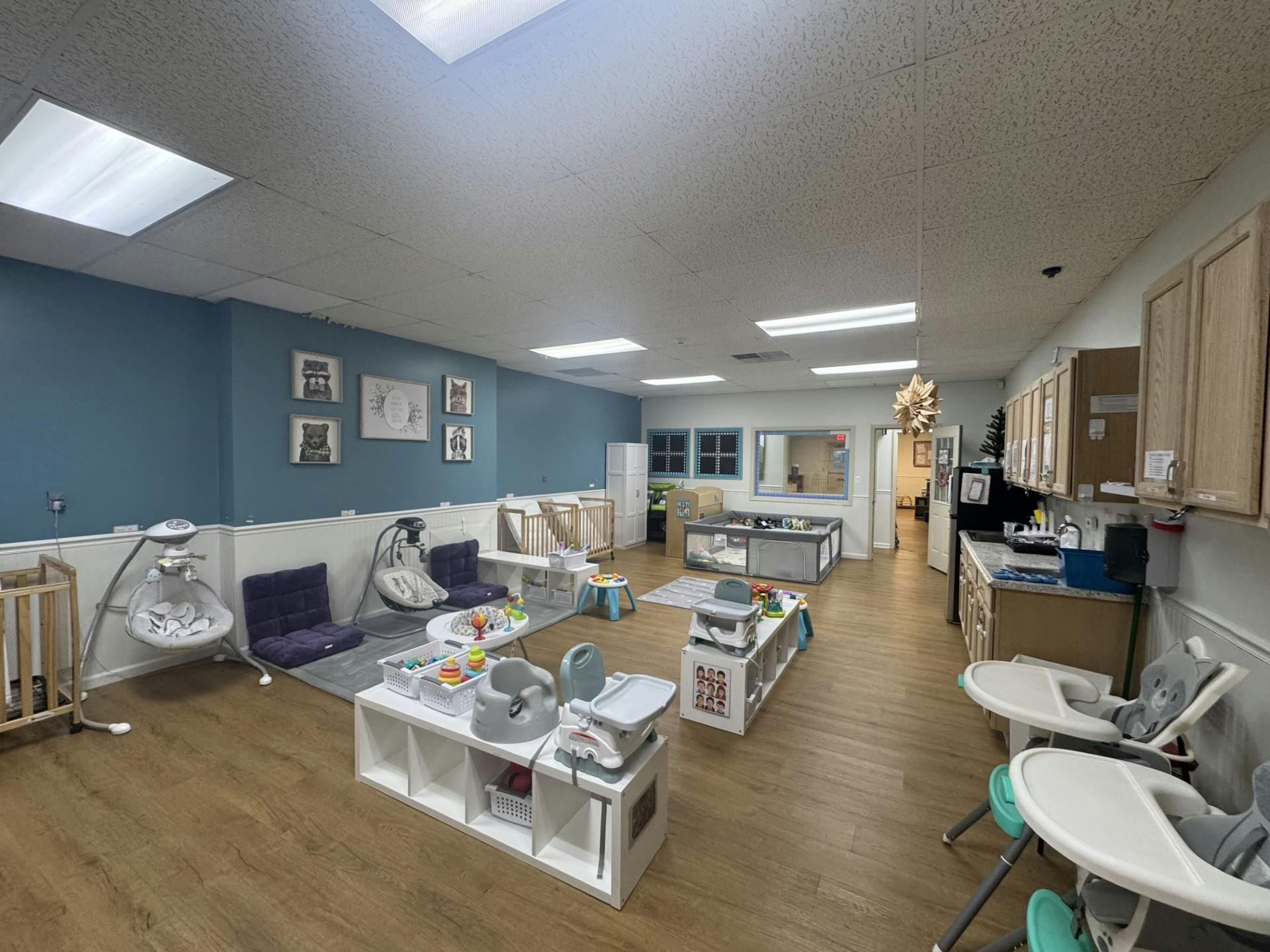 Baby and toddler play area with cribs, swings, high chairs, and shelves of toys