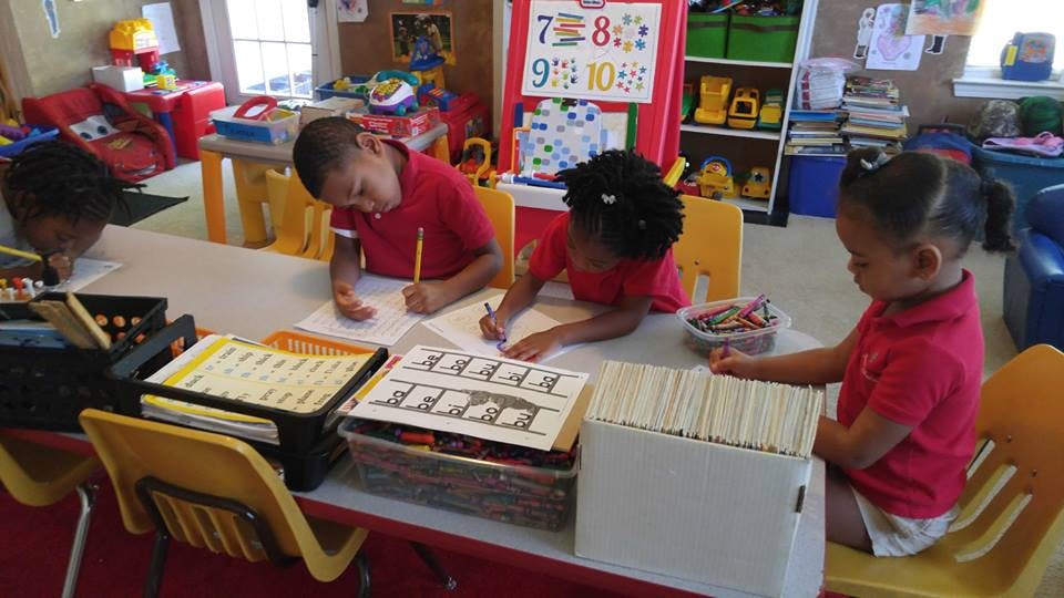 Four children sitting at a table drawing