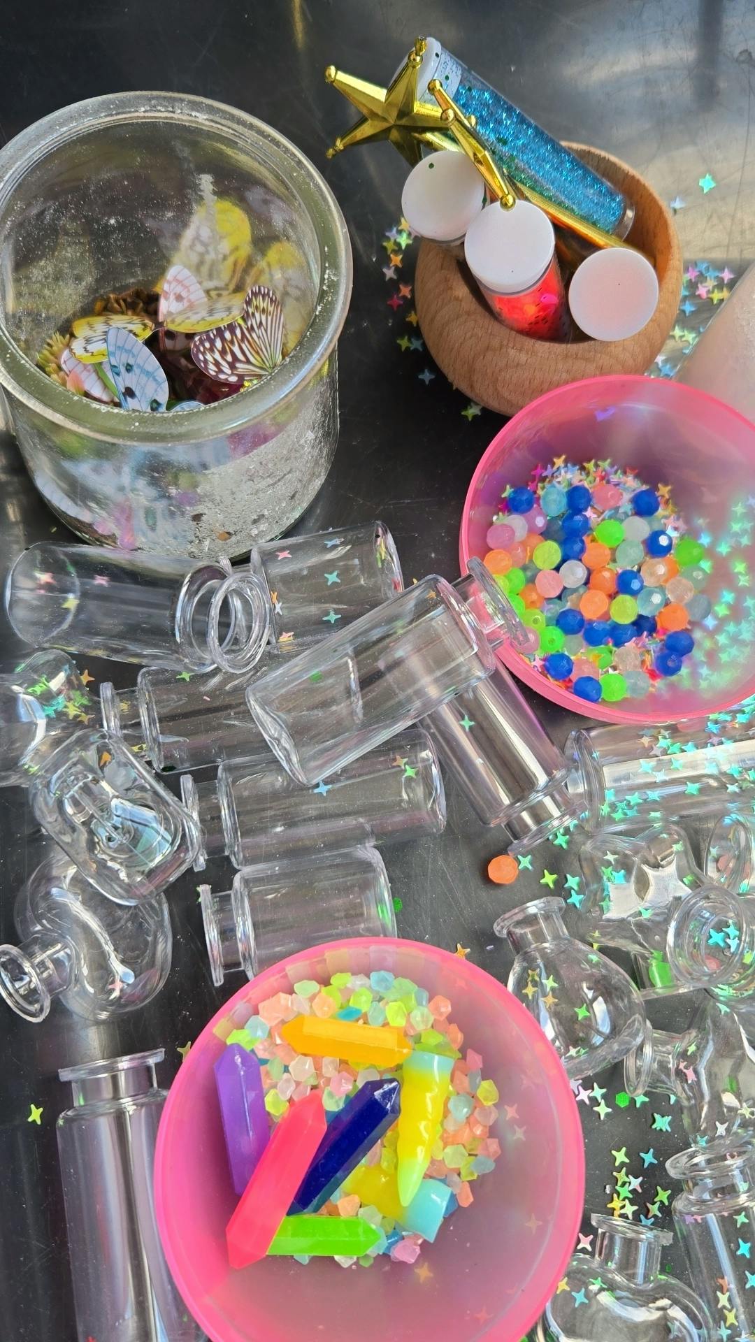 Craft supplies including miniature bottles, colorful beads, and decorative butterflies